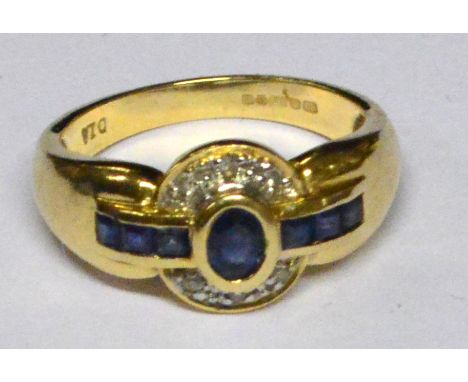 A 14ct yellow gold Art Deco style sapphire and diamond ring with central collet set oval sapphire flanked by three small sapp