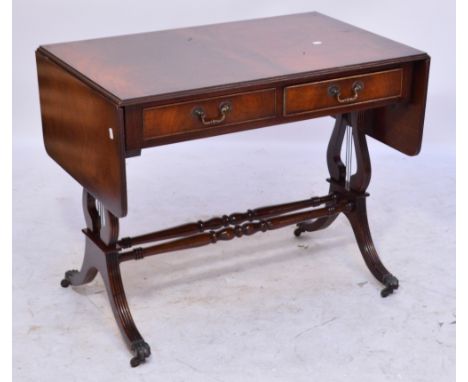 A reproduction mahogany two drawer sofa table with supports united by two turned stretchers, on fluted sabre legs with gilt m