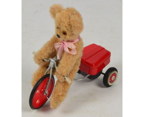 A vintage bear on a metal, plastic and tinplate bicycle which pedals as it is pulled along, length 17cm.