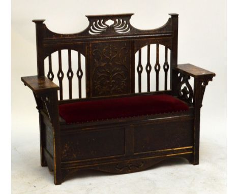 An oak Arts and Crafts box seat hall bench with shaped pediment above carved central panel decorated with foliate scrolls abo