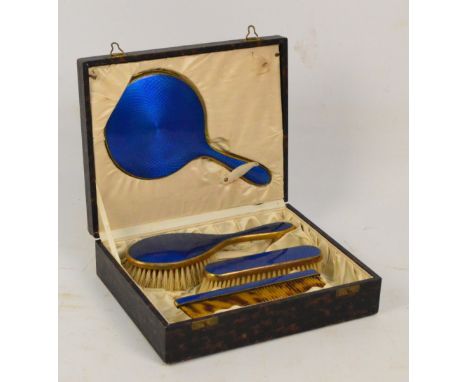 A cased three piece base metal and blue guilloche enamel decorated dressing table set comprising a hand mirror, length 23.5cm