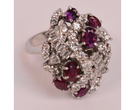 A white metal diamond and ruby cluster ring, the lozenge shaped platform stepped with various cut diamonds interspersed by si