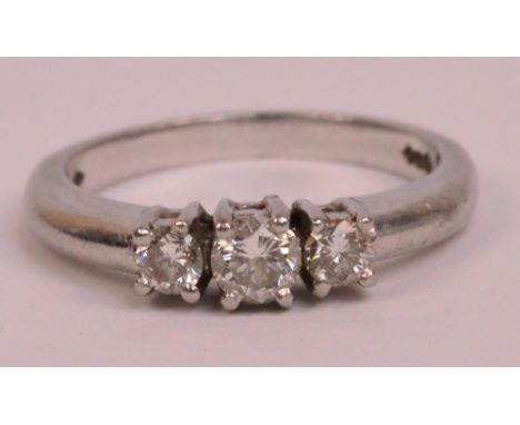 A platinum and diamond three stone graduated ring, the central diamond weighing approximately 0.15 cts, size K, approx 4.7g.