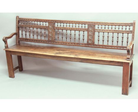 OAK HALL BENCH, 19th century, the spindle back with foliate panels on a solid seat, 97cm, width 198cm, depth 39cm