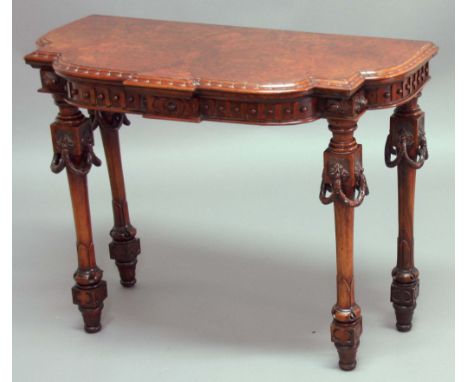 VICTORIAN WALNUT CARD TABLE, of shaped serpentine form, with moulded frieze, the legs with carved swags, cylindrical legs and