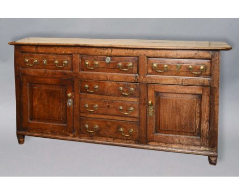 GEORGE III OAK DRESSER BASE, the canted rectangular top above three fielded freize drawers and a run of three drawers flanked
