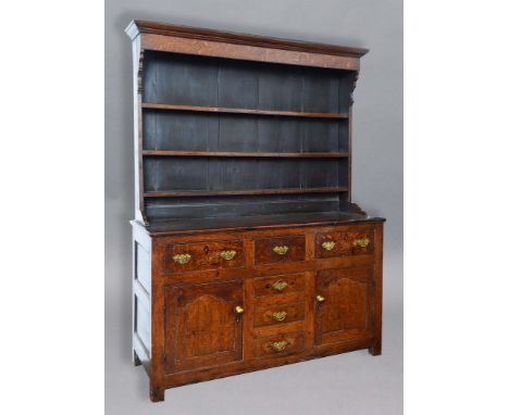 GEORGE III OAK DRESSER, probably Anglesey, the three shelf plate rack on a base with a 'T' arrangement of drawers and a pair 