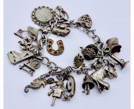 A silver charm bracelet with a collection of charms including a Dunce's cap, stick telephone, sea horse etc. total weight 65.