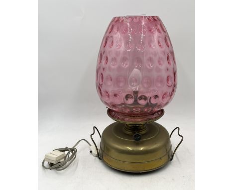 An antique brass oil lamp with large cranberry shade