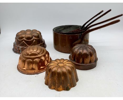 Four assorted vintage copper jelly moulds, and a set of four vintage French copper saucepans.