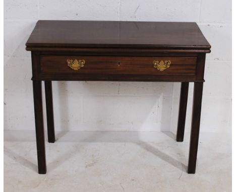 A Georgian mahogany folding tea table, with single drawer with brass handles, raised on stick legs