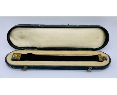 A Victorian velvet bracelet with silver-gilt mounts clasp decorated with turquoise and ruby in the original fitted box.