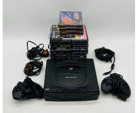 An unboxed Sega Saturn computer console with two controllers, power cables and selection of games including Myst, Virtua Figh