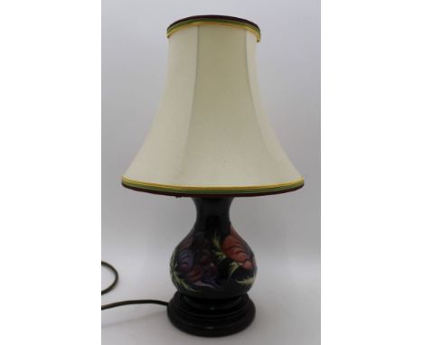 A MOORCROFT POTTERY TABLE LAMP of tear drop form, blue ground, tube lined and painted anemone decoration, on polished wood ba
