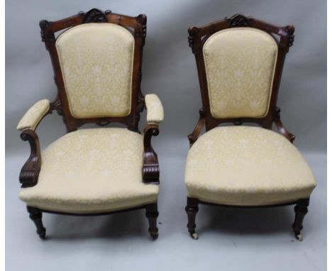 A LATE 19TH CENTURY WALNUT FRAMED HIS &amp; HER SALON CHAIR with fancy carved crest rail, having buttermilk damask upholstere