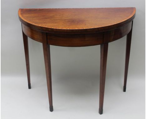 A LATE GEORGIAN MAHOGANY FOLD-OVER CARD TABLE having satinwood crossbanded top &amp; strung apron with four tapering legs wit