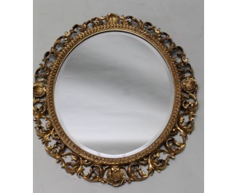 AN EARLY 20TH CENTURY OVAL BEVEL PLATE WALL MIRROR, with Florentine carved and gilded wooden gesso frame, having continuous R