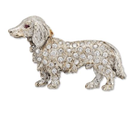 A diamond set dog brooch, in the form of a dachshund, with brilliant-cut diamond set body and ruby set eyes, width 4.1cm (VAT