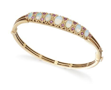 A 9ct gold opal and ruby bangle, the top half with a row of graduated cabochon opals, with pairs of mixed cut rubies between,