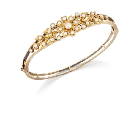 An Edwardian gold seed pearl and half-pearl hinged bangle, with central flowerhead cluster motif and foliate shoulders to ope