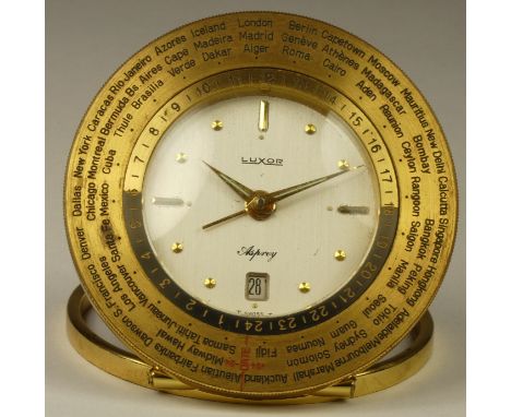 An Asprey Luxor 8 day world time desk alarm and date brass clock, with 66 countries to the rotating bezel, diameter 8cm, numb