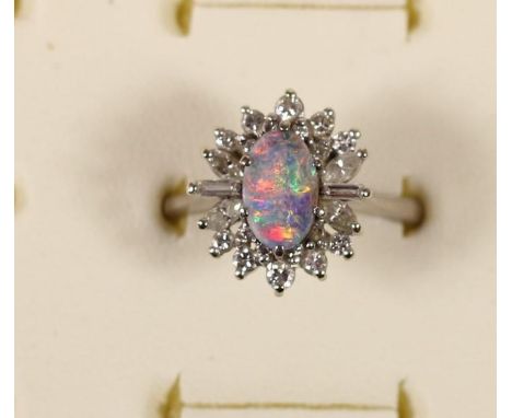 An 18ct white gold black opal doublet and diamond cluster ring, London 1973, claw set with brilliant, baguette and navette cu