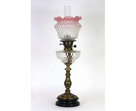 A brass oil lamp, with clear glass font and cranberry tinted shade, 68cm in extremes 