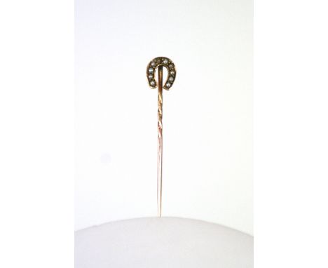 A yellow metal and seed pearl horseshoe stick pin