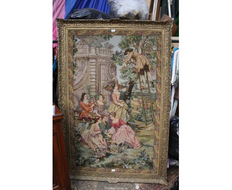 A large gilt framed wool tapestry ably depicting a classical garden scene with a gentleman in early dress balanced on a ladde