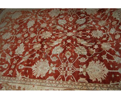 PERSIAN BORDERED CARPET WITH STYLIZED FLORAL PATTERN ON A CLARET COLOURED GROUND. 390CM LONG X 294CM WIDE.