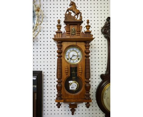 A contemporary wooden wall clock with decorative horse finial. 