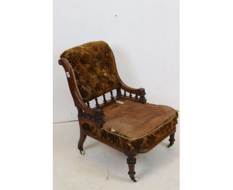 Victorian carved walnut low armchair of designer influence, with velvet button back and padded arms, on turned tapering flute