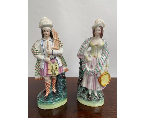 A Pair of Antique Staffordshire Scottish man and lady figurine. Man playing bagpipes and the lady is playing the tambourine. 