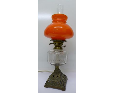 A converted oil lamp with orange glass shade