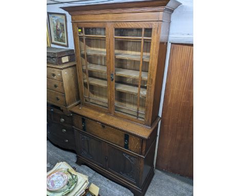 A Victorian oak bookcase secretaire, the top with dentil moulded cornice above twin glazed doors and interior shelves, the ba