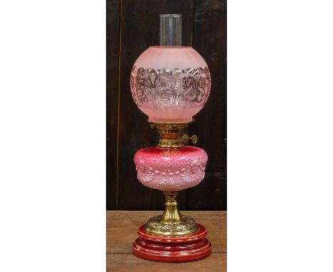 An Art Nouveau oil lamp, pink glass reservoir and shade, embossed brass foot on a stepped base