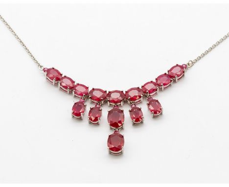 A ruby and silver drop necklace, comprising a row of graduated oval rubies suspending a central dropper of two lager oval cut