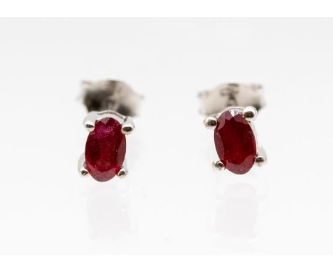 A pair of ruby and silver stud earrings comprising claw set oval cut rubies, weighing approx. 0.71ct,&nbsp;on post and scroll