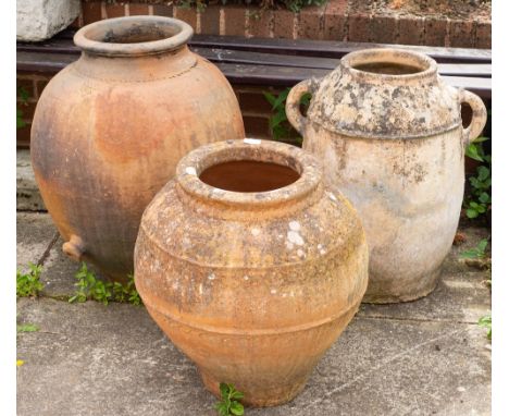 Three terracotta garden pots, 20th century,: the largest example, ovoid and with a spout close to the base, 68cm high; the tw