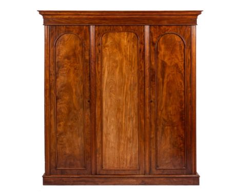 A Victorian mahogany three door wardrobe, circa 1875,: with ogee moulded cornice above three arched panel doors, the first tw