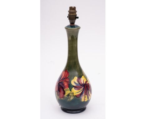 A Moorcroft pottery lamp: of slender pear shaped form tube lined in the Hibiscus pattern in yellow, red, purple and blue on a