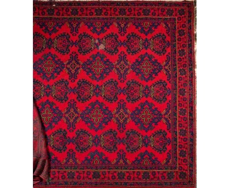 A Turkey carpet:, of large size and traditional design and colours, the red field with all over hooked geometric medallions, 