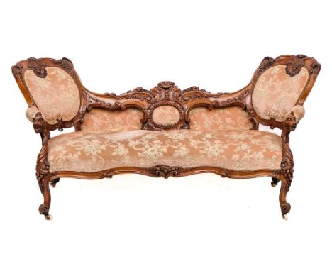 A Victorian carved walnut and upholstered love seat, circa 1870,: with a backrest at each end above a shaped seat; the showfr