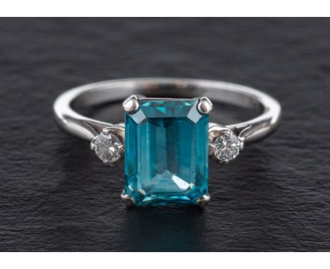 A step-cut blue topaz and round, brilliant-cut diamond three stone ring,: calculated topaz weight ca. 2.50cts, estimated tota