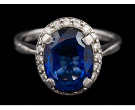 A diffusion treated sapphire and diamond ring,: the oval cut diffusion treated sapphire claw set within a surround of brillia