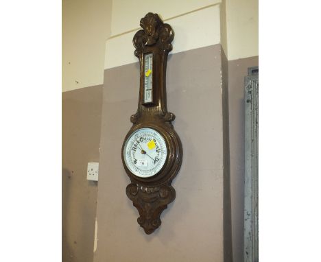 A SMALL OAK CARVED ANEROID BAROMETER H-79 CM