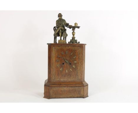   Pendule in palissander kast bekroond met metalen sculptuur van  zittende figuur aan tafel, ca. 1880, h. 48 cm.        Mante