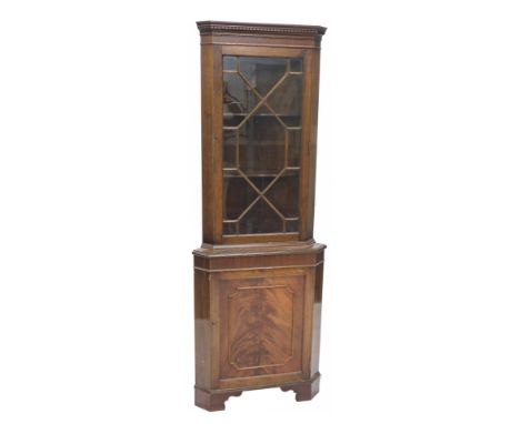 A mahogany standing corner cabinet with a single glazed door and a panel door on bracket feet. 