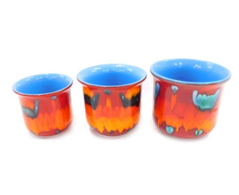 A graduated set of three Poole Delphis style jardinieres, each decorated in shades of red, orange, turquoise and powder blue,