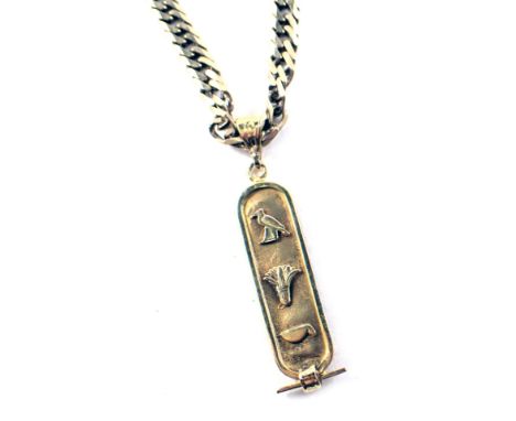 An Egyptian ingot pendant and chain, the oval shaped ingot with addition pharaohs, on a figaro neck chain, yellow metal stamp